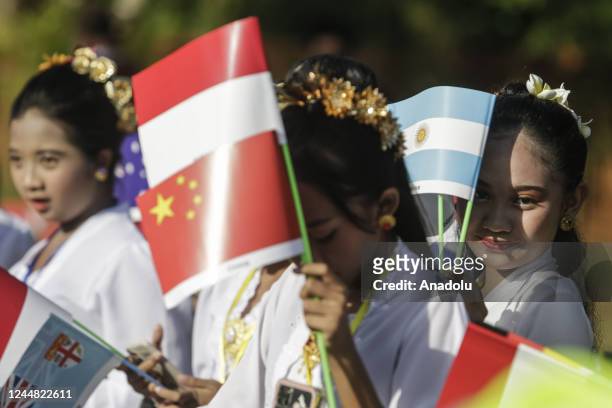 Balinese kids hold flags as they wait for head of state's vehicles passes to Tahura Mangrove Forest within G20 Leaders' Summit in Nusa Dua, Bali,...