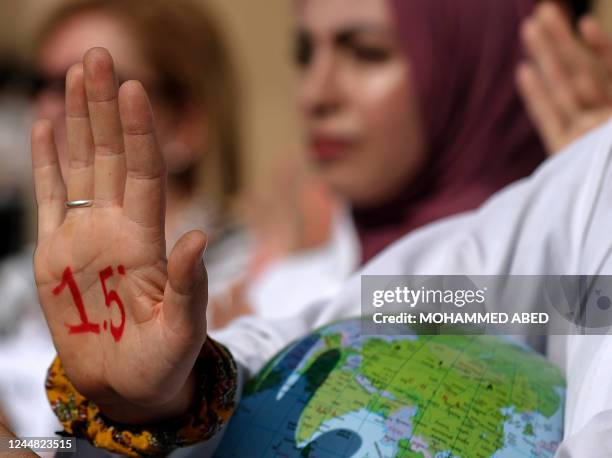 An activist with paint on her hand reading "1.5 degrees", alluding to demands to limit global temperature rise to 1.5 degrees Celsius compared to...