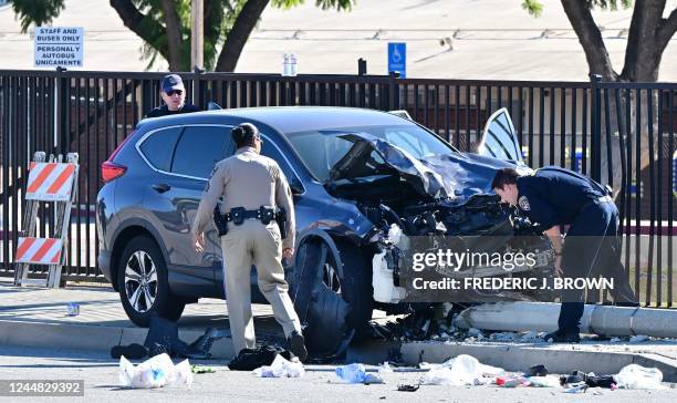 Law enforcement personnel take a closer look at the destruction of an SUV involved in critically injuring nearly two dozen deputy recruits in a Los...