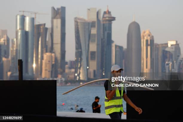 Worker carries wood at a construction site at the Corniche in Doha on November 16 ahead of the Qatar 2022 FIFA World Cup football tournament.