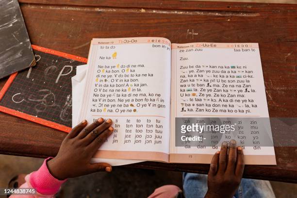 Young girl uses a book to learn Bambara, one of Malis main national languages, in a school in Bamako on November 10, 2022. - In Mali, a few words in...