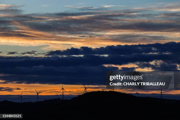Photograph taken from Roquefort-sur-Soulzon, southern France on November 16, 2022 shows wind turbines working at sunset.