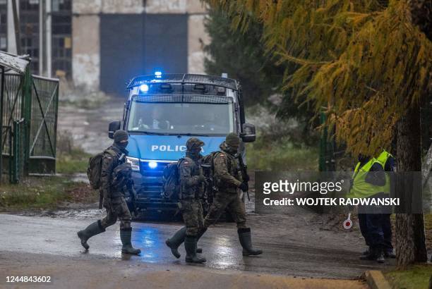Polish soldiers pass on November 17, 2022 by the police check point next to site where a missile strike killed two men in the eastern Poland village...