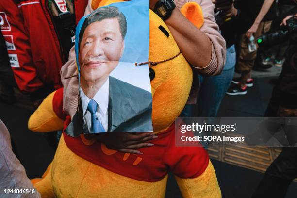 Protester holds a pooh bear with a poster of Xi Jinping during the demonstration. Pro-democracy protesters gathered at Asok intersection near Queen...