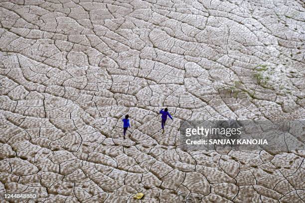 Boys run along the dried-up portion of a riverbed on the banks of river Ganges in Prayagraj, on November 17, 2022.