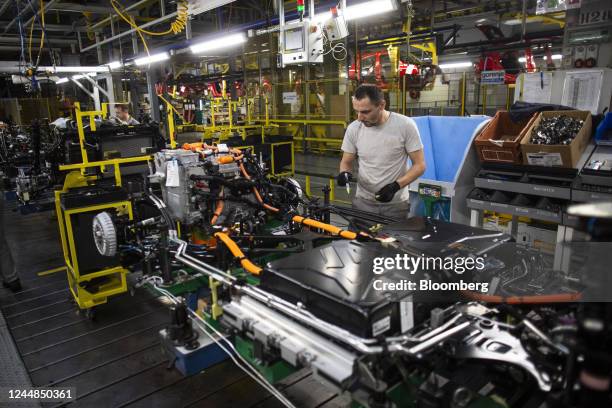 An employee connects the drive train system and battery module to the chassis of a Renault Twingo Electric automobile on the production line at the...