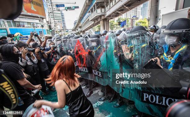 Pro-democracy protester throw a bucket of paint toward riot police officers during an anti-government demonstration nearby the site of the APEC 2022...