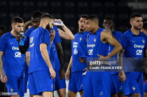 France's forward Karim Benzema speaks with France's forward Kylian Mbappe during a training session at the Jassim-bin-Hamad Stadium in Doha on...