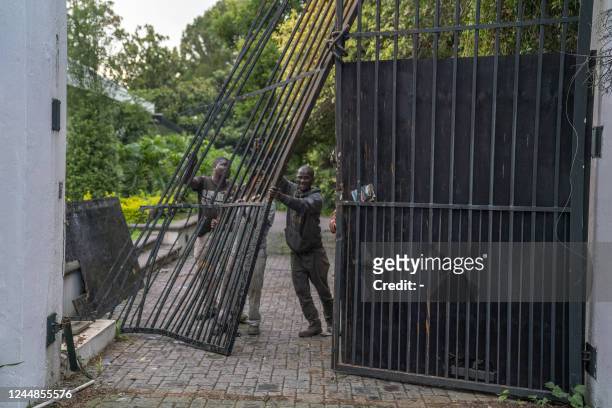 Workers repair a gate after it was rammed by an armoured vehicle of the South African Police Service during a raid at a house in Bryanston,...