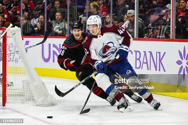 Josh Manson of the Colorado Avalanche controls the puck behind the net and away from Martin Necas of the Carolina Hurricanes who pursues during an...