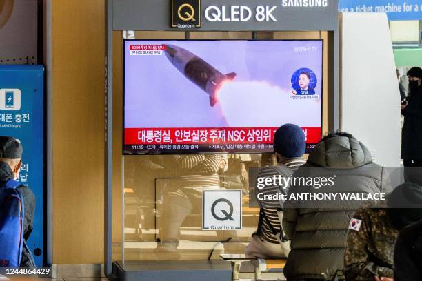 People sit near a television showing a news broadcast with file footage of a North Korean missile test, at a railway station in Seoul on November 18,...