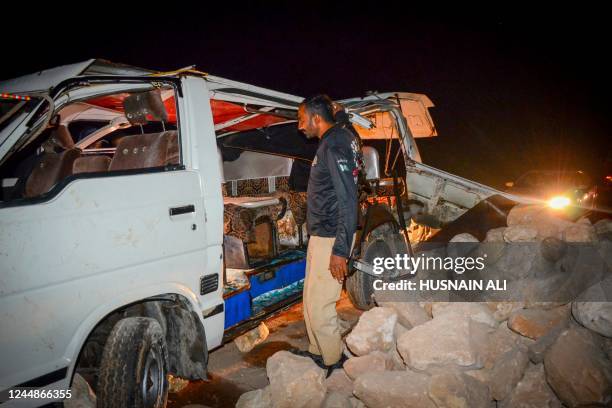 Policeman stands beside a damaged passenger mini bus after an overnight accident in Sehwan of Sindh province on November 18, 2022. At least 20 people...