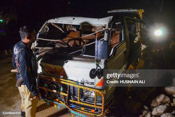 Policeman stands beside a damaged passenger mini bus after an overnight accident in Sehwan of Sindh province on November 18, 2022. At least 20 people...