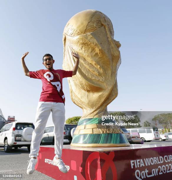 Football fan jumps in front of a giant replica of the golden World Cup trophy in Qatar's capital city Doha, on Nov. 10, 2022.