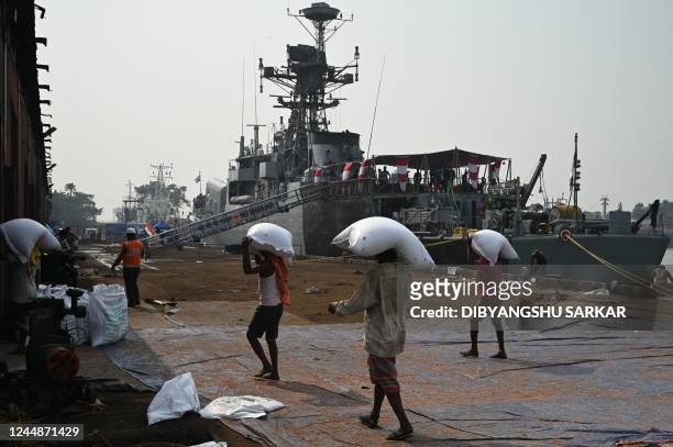 Labourers carry imported sacks of food grains to godown next to the INS Khanjar, a guided missile corvette, docked at the Kolkata Port Trust dock for...
