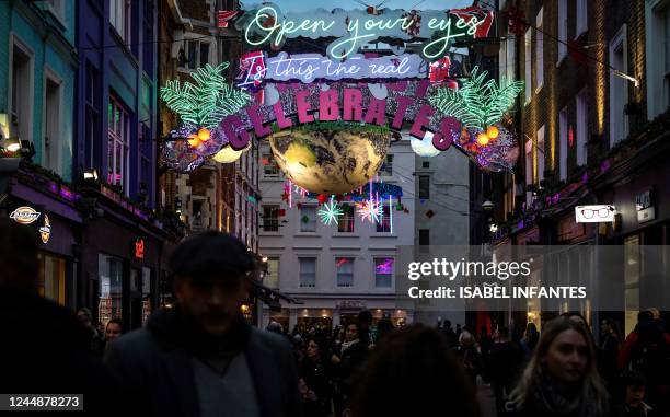 People walk past Christmas decorations set in Carnaby street, central London, on November 18, 2022.