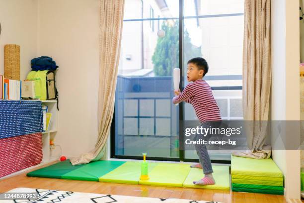 little boy playing baseball in living room at home - japanese baseball players strike stock pictures, royalty-free photos & images