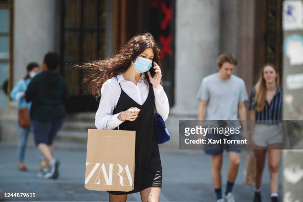 Woman wearing a protective mask is carrying a bag with her recent purchase from a Zara store on June 03, 2020 in Barcelona, Spain. In all open...