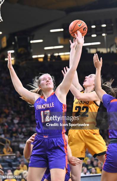 Iowa guard Caitlin Clark puts up a shot as Evansville forward Celine Dupont defends during a women's college basketball game between the Evansville...