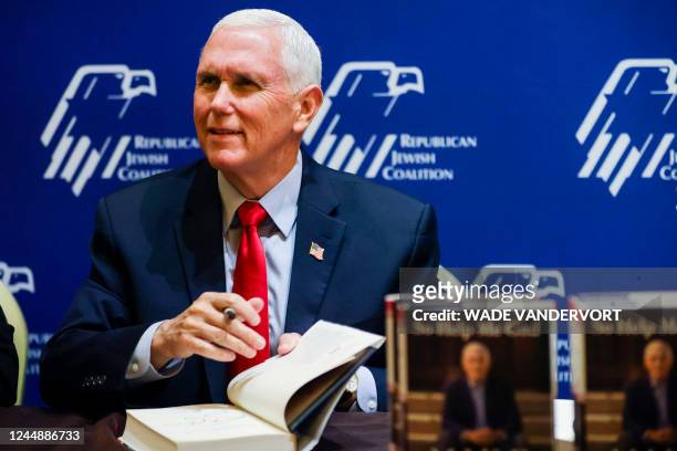 Former US Vice President Mike Pence signs a copy of his book "So Help Me God" for a supporter during the Republican Jewish Coalition Annual...