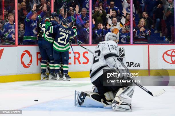 Brock Boeser is congratulated by Jacob Moverare and Nils Hoglander of the Vancouver Canucks after scoring a goal as Jonathan Quick of the Los Angeles...