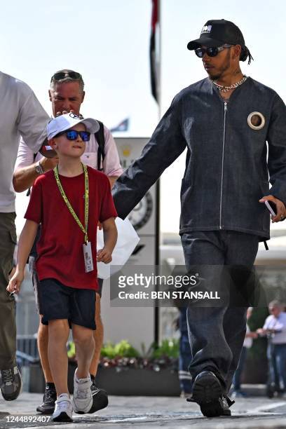 Mercedes' British driver Lewis Hamilton greets a young fan as he arrives for the third practice session ahead of the Abu Dhabi Formula One Grand Prix...