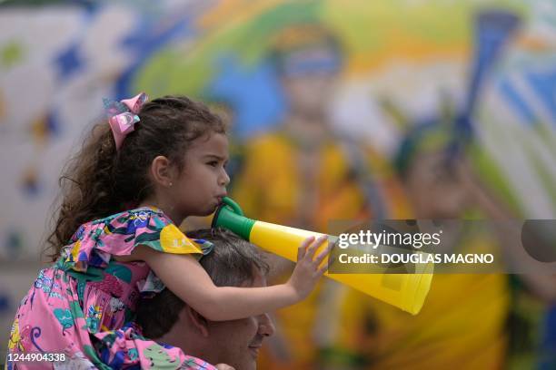 Girl blows a vuvuzela in front of disused plane decorated with themes of the Brazilian national football team at a shopping mall in Contagem, Minas...