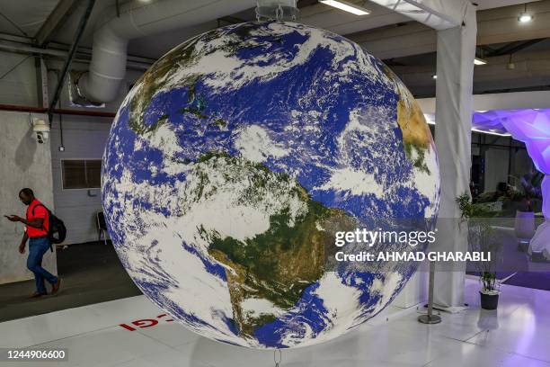 Person walks near a mockup depicting the Earth globe at a booth in the deserted hall at the Sharm el-Sheikh International Convention Centre, in...