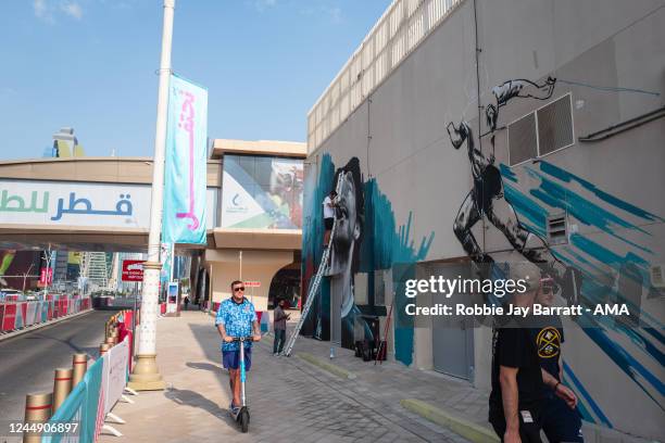 Local graffiti artist Cass Art in the process of painting a mural of Diego Maradona outside of West Bay metro station as a fan of England goes by on...