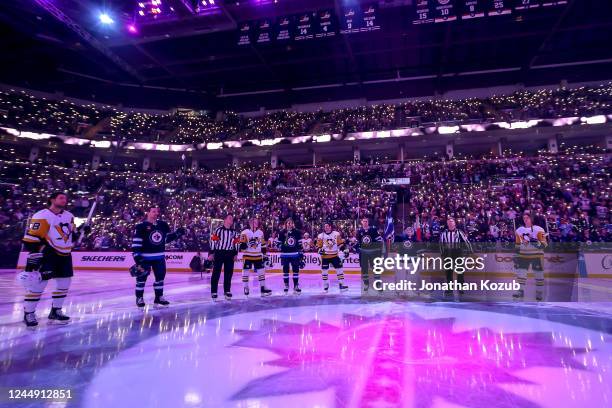 Members of the Winnipeg Jets and the Pittsburgh Penguins raise their sticks at centre ice while fans light up the stands in support of the Hockey...