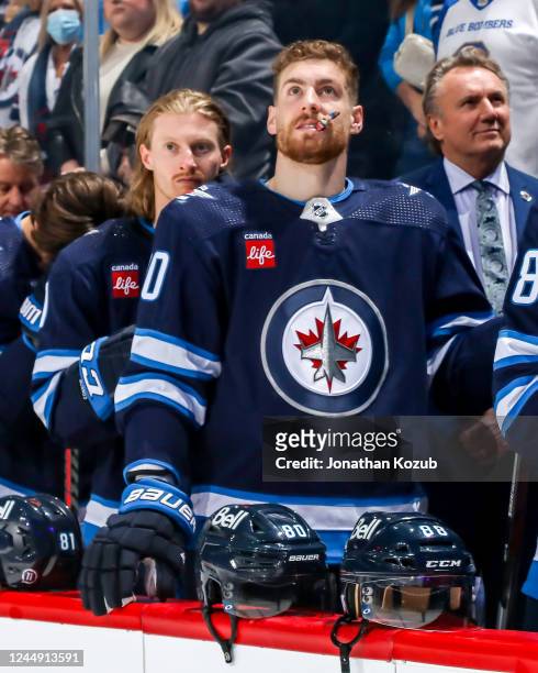 Kyle Connor and Pierre-Luc Dubois of the Winnipeg Jets stand on the bench during the singing of the National anthems prior to puck drop against the...