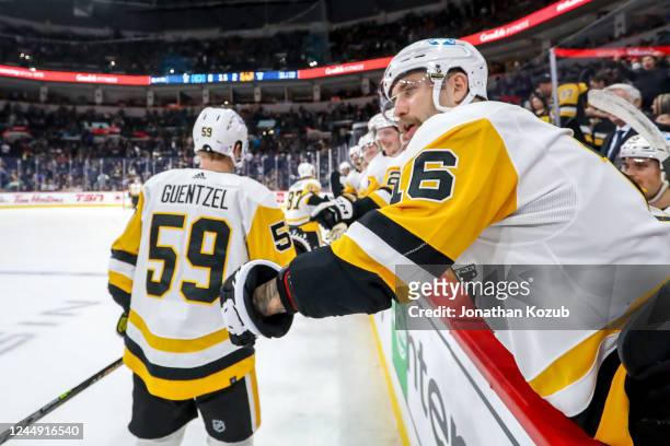 Jake Guentzel of the Pittsburgh Penguins celebrates his third period empty net goal against the Winnipeg Jets with teammates at the bench at the...