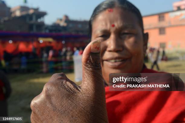 Voter holds up her thumb marked with indelible ink by an election official after casting her vote in the general election at a polling station in...