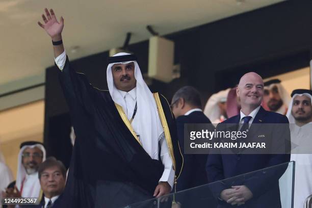 Qatar's Emir Sheikh Tamim bin Hamad al-Thani waves to the crowd as he arrives with FIFA President Gianni Infantino for the Qatar 2022 World Cup Group...