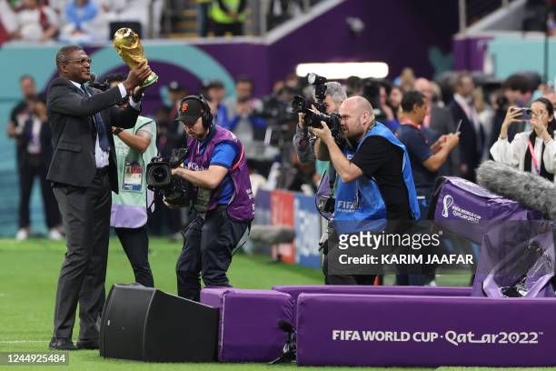 French former football player Marcel Desailly holds the FIFA World Cup trophy ahead of the Qatar 2022 World Cup Group A football match between Qatar...