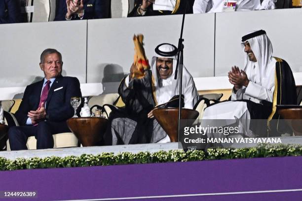 Qatar's former Emir Sheikh Hamad bin Khalifa al-Thani and Qatar's Emir Sheikh Tamim bin Hamad al-Thani waves a signed Qatari jersey next to Qatar's...