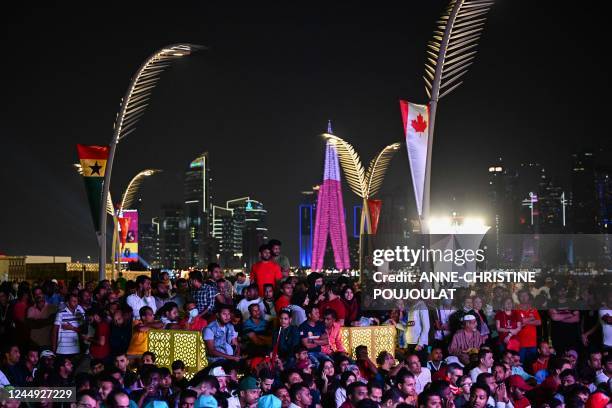 People gather to watch a live broadcast of the opening ceremony of the Qatar 2022 World Cup football tournament, at the Corniche of Doha on November...