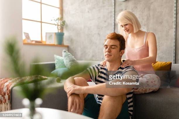 serene boyfriend enjoying back massage from a caring girlfriend in the morning - girlfriend massage stock pictures, royalty-free photos & images