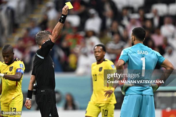Italian referee Daniele Orsato shows a yellow card to Qatar's goalkeeper Saad Al Sheeb during the Qatar 2022 World Cup Group A football match between...