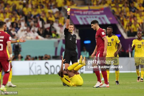 Italian referee Daniele Orsato shows a yellow card to Qatar's midfielder Karim Boudiaf after he tackled Ecuador's forward Enner Valencia during the...