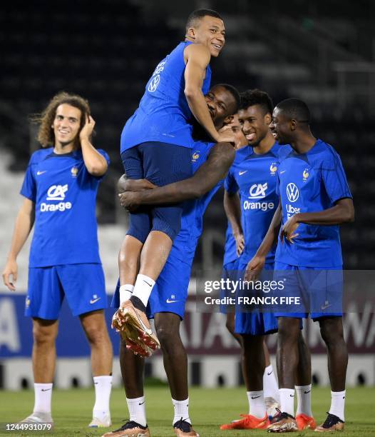 France's forward Marcus Thuram jokes with France's forward Kylian Mbappe during a training session at the Jassim-bin-Hamad Stadium in Doha on...