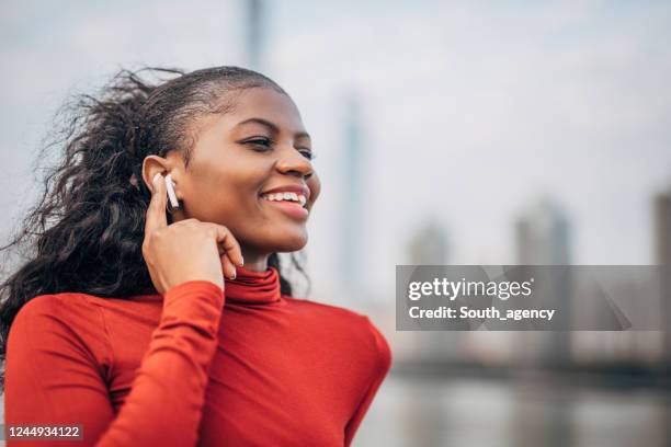 une femme écoutant la musique sur des écouteurs sans fil au bord de la rivière - in ear headphones photos et images de collection