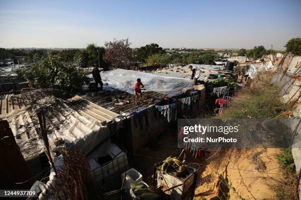 Palestinian man lays a sheet of plastic to cover the roof of a shack from the effects of bad weather in Gaza City on November 20, 2022.