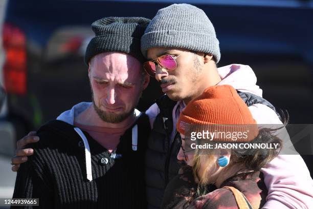 Tyler Johnston, his fiance, Keenan Mestas-Holmes, and Altas Pretzeus embrace while paying their repsects at a memorial for the vicitms of the mass...