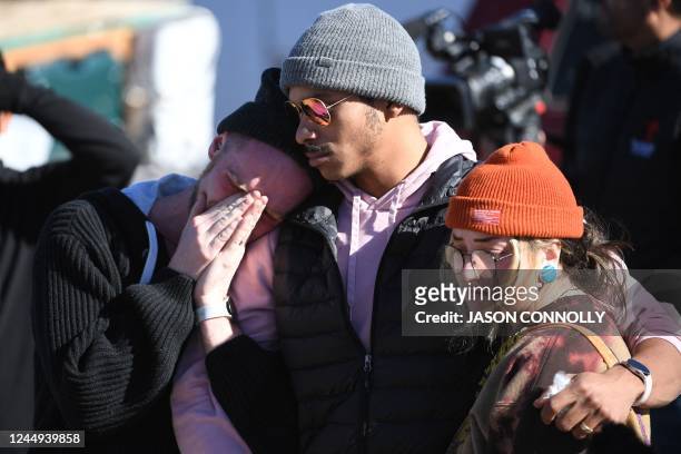 Tyler Johnston, his fiance, Keenan Mestas-Holmes, and Altas Pretzeus embrace while paying their repsects at a memorial for the vicitms of the mass...