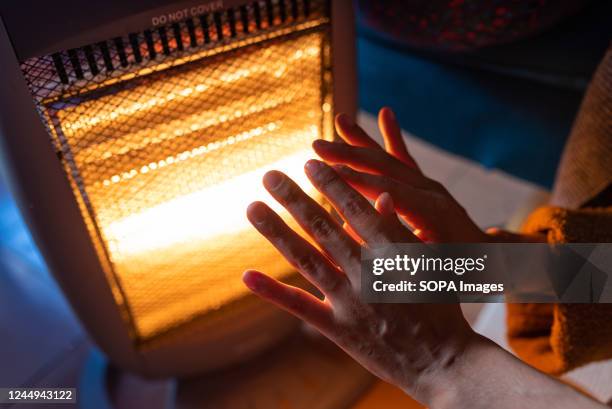 Woman warms her hands on an electric heater at home in the Guinardo neighborhood. The increasing cost of natural gas following the Russia-Ukraine war...