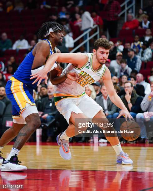 Alperen Sengun of the Houston Rockets dribbles the ball against Kevon Looney of the Golden State Warriors during the game at Toyota Center on...