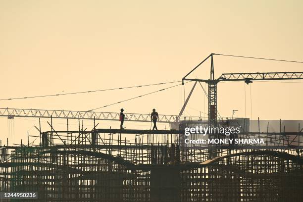 Workers are silhouetted on a scaffolding at an under-construction flyover site in New Delhi on November 21, 2022.