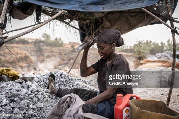 Briggite, a former hairdresser who lost everything in 2011 during a flood, breaks granite into smaller pieces in a granite mine in Ouagadougou,...