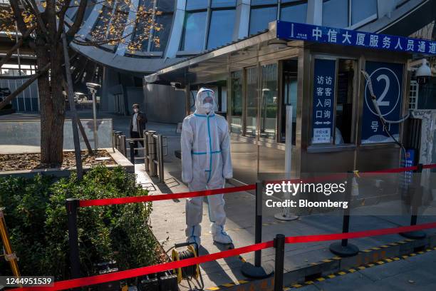 Worker in protective gear at an entrance to the Citic Tower in Beijing, China, on Monday, Nov. 21, 2022. Surging infections are threatening to...